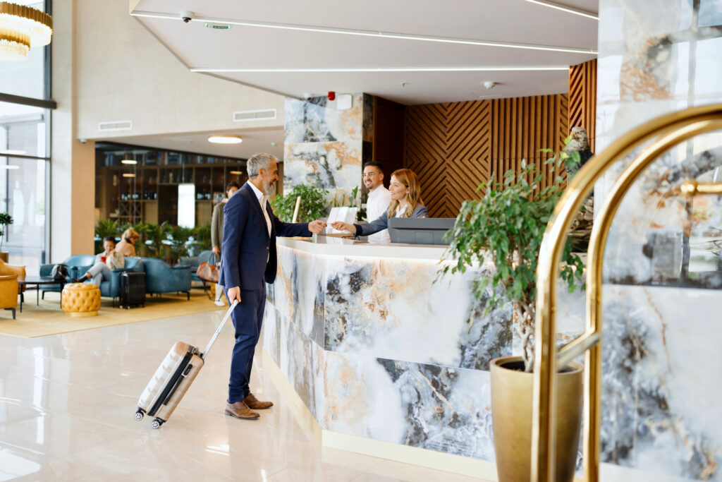Elegantly dressed businessman talking with a receptionist while checking out from the hotel