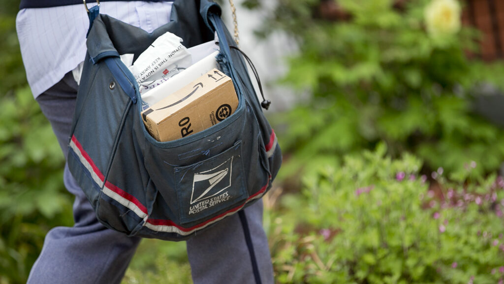 U.S. Postal Service (USPS) letter carrier Sharon Herbert carries a mailbag while delivering mail in Washington, D.C., U.S., on Thursday, May 9, 2013. The